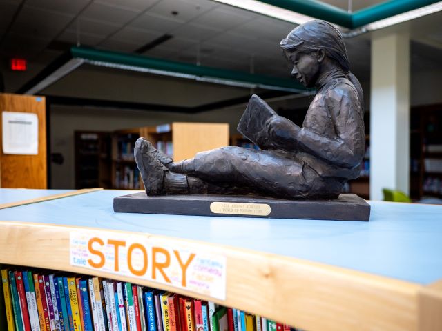 A charming statue of a girl engrossed in a book rests on a shelf, enhancing the cozy atmosphere of the space.