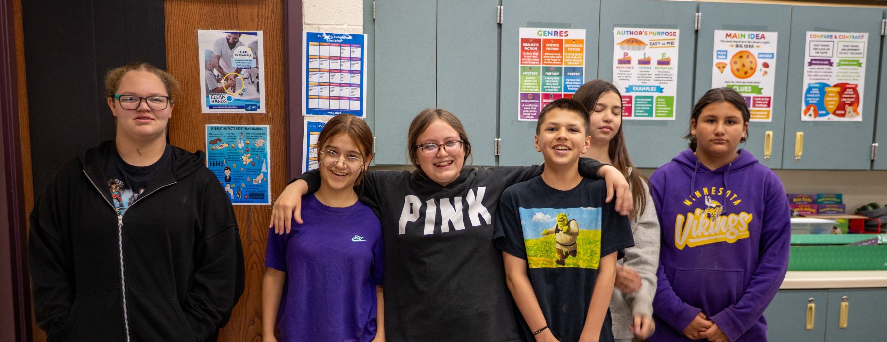 A group of students smiling and standing together in front of a classroom door, ready for their lesson.