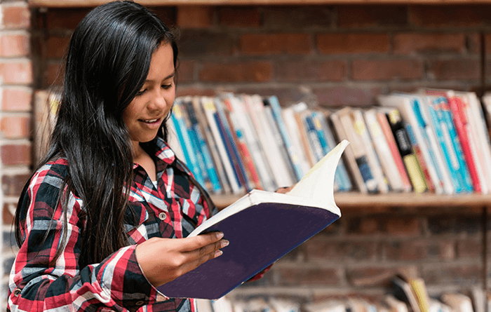 Female student reading a book in the library.